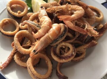 fried sea food on a plate. Fresh shrimps, calamari.